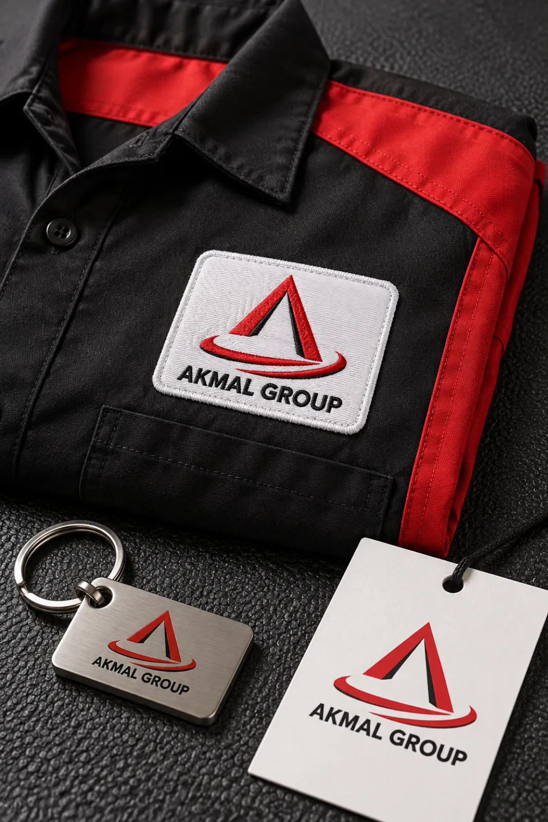 An Akmal Group work shirt, key fob and service tag on a black workbench mat