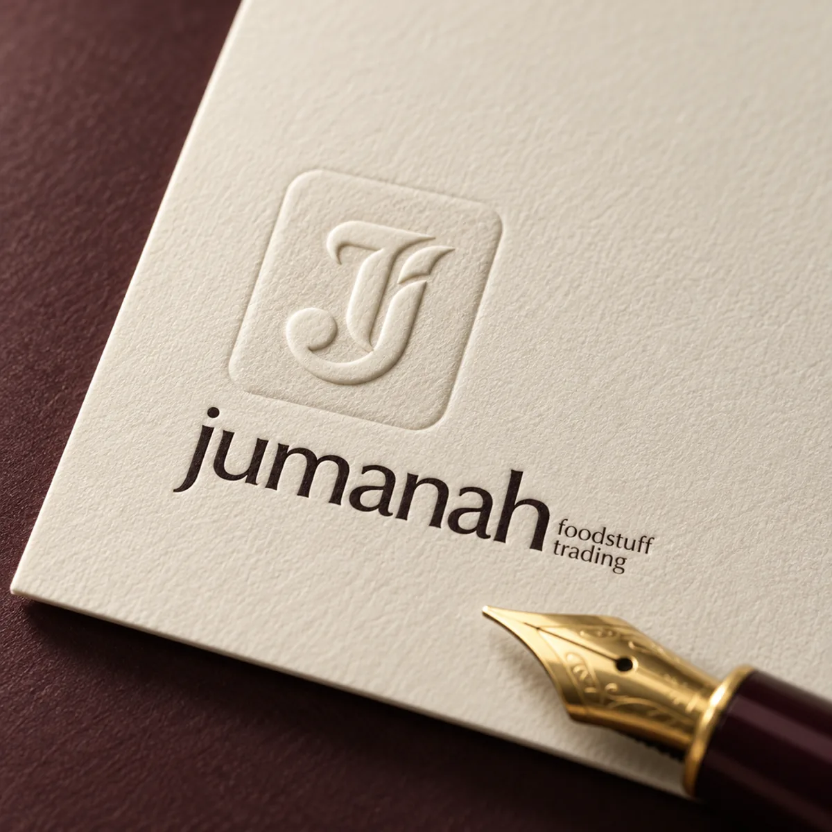 A Jumanah Foods letterhead with a blind-embossed monogram and a gold fountain pen nib