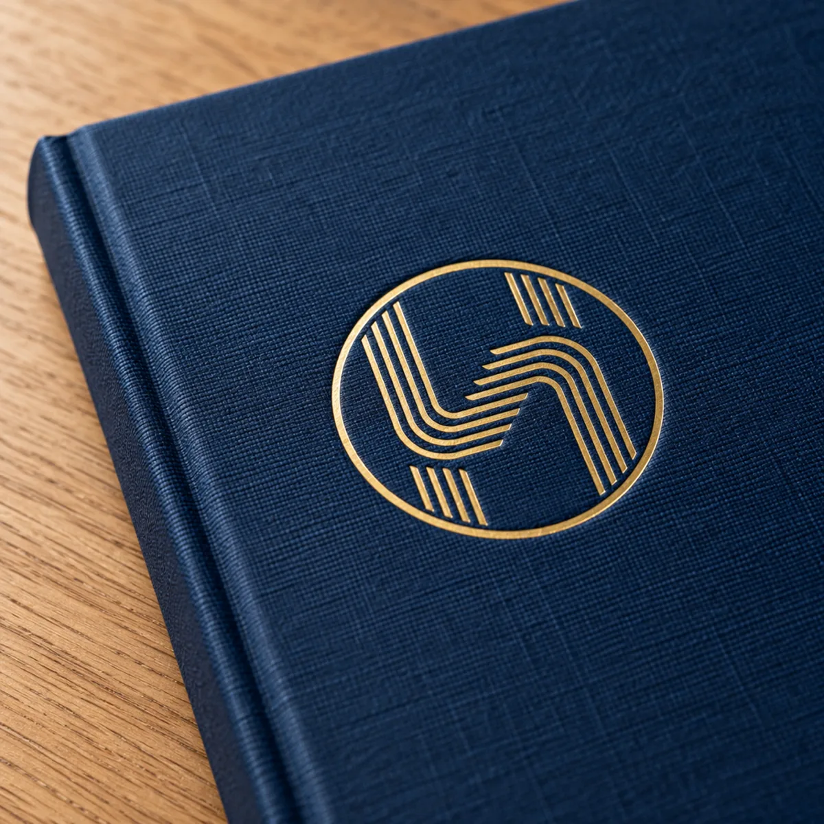 A navy cloth bound company profile with a gold foil Trus Holding emblem on an oak table