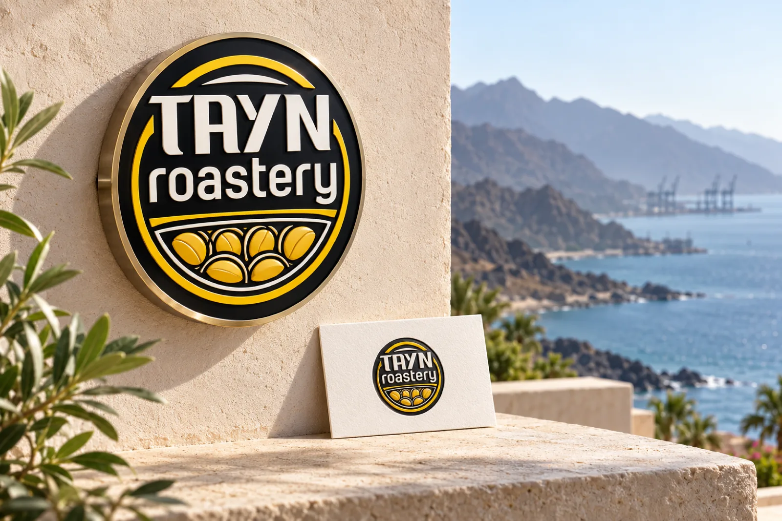 A dimensional logo sign and embossed business card for Tayn Roastery in a calm setting, with mountains meeting the sea in Fujairah softly in the background.