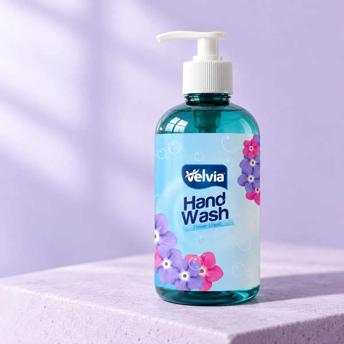 A Velvia hand wash bottle with a printed flower label on a lilac stone plinth
