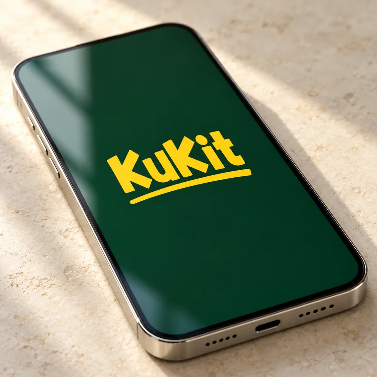 A close-up of a phone on a stone surface with the yellow KuKit wordmark on a deep green screen.
