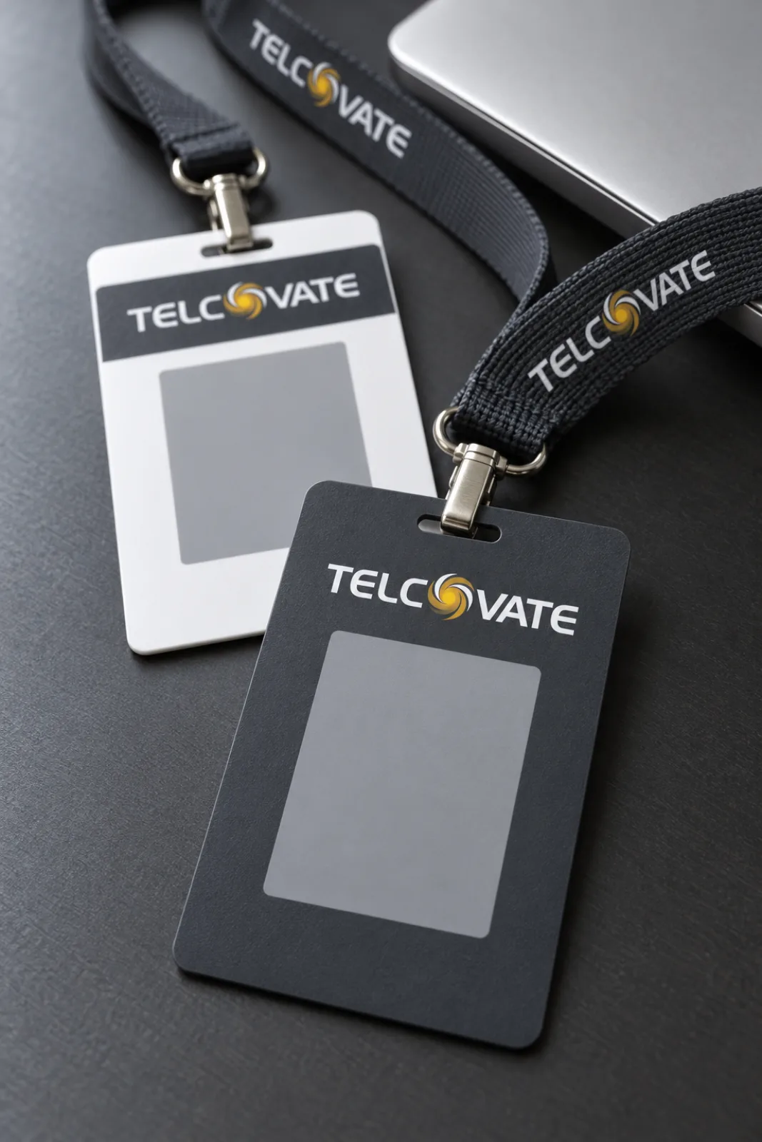 Telcovate staff ID cards on charcoal printed lanyards on a desk