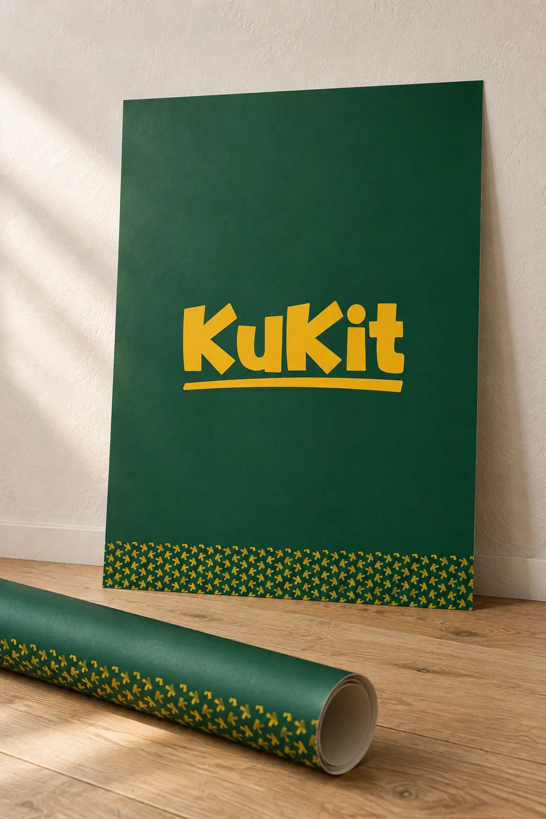 A green Kukit poster with a yellow pattern strip leaning on a plaster wall beside a rolled sheet