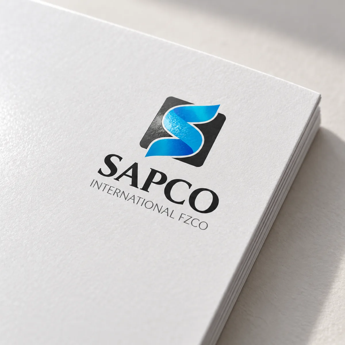 Close-up of the Sapco logo on the cover of a white brochure with a soft spot gloss