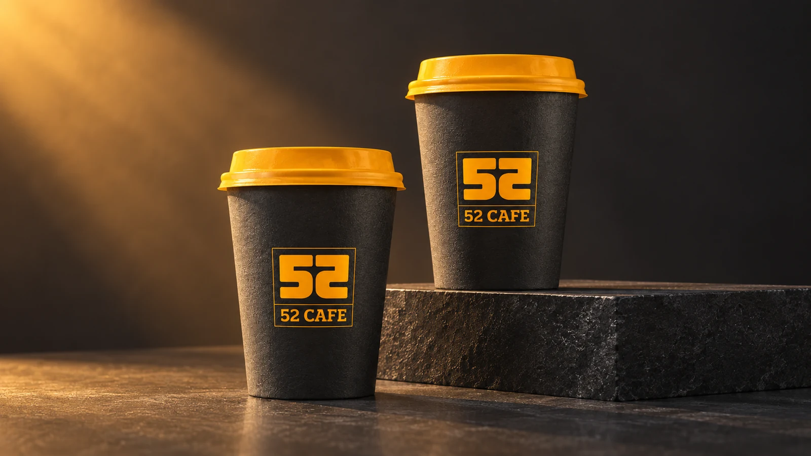 52 Cafe: two charcoal takeaway cups with orange lids and the mirrored 52 monogram, presentation cover