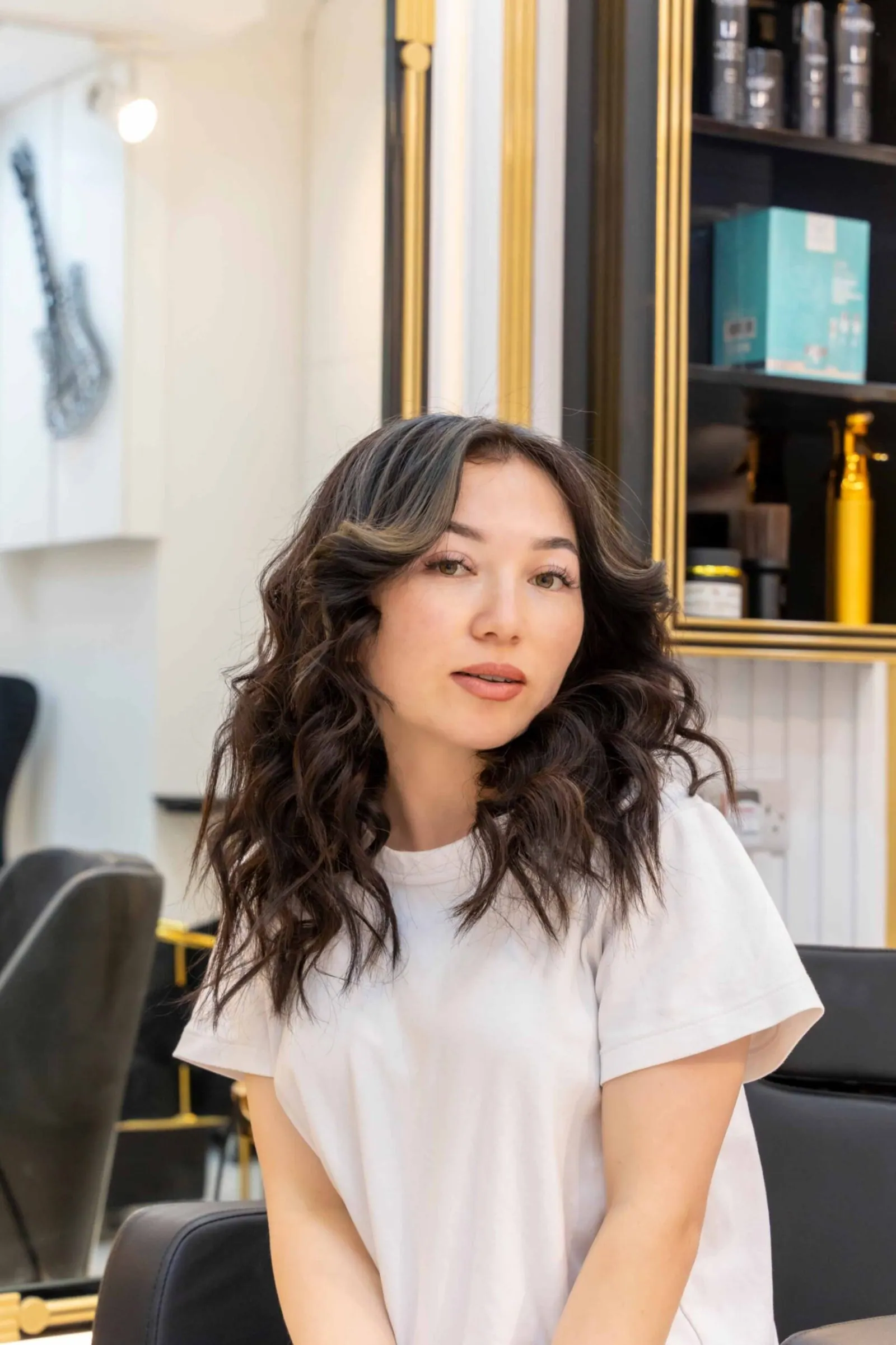 Salon photography: a portrait of a client with long curls, with salon mirrors and product shelves behind.