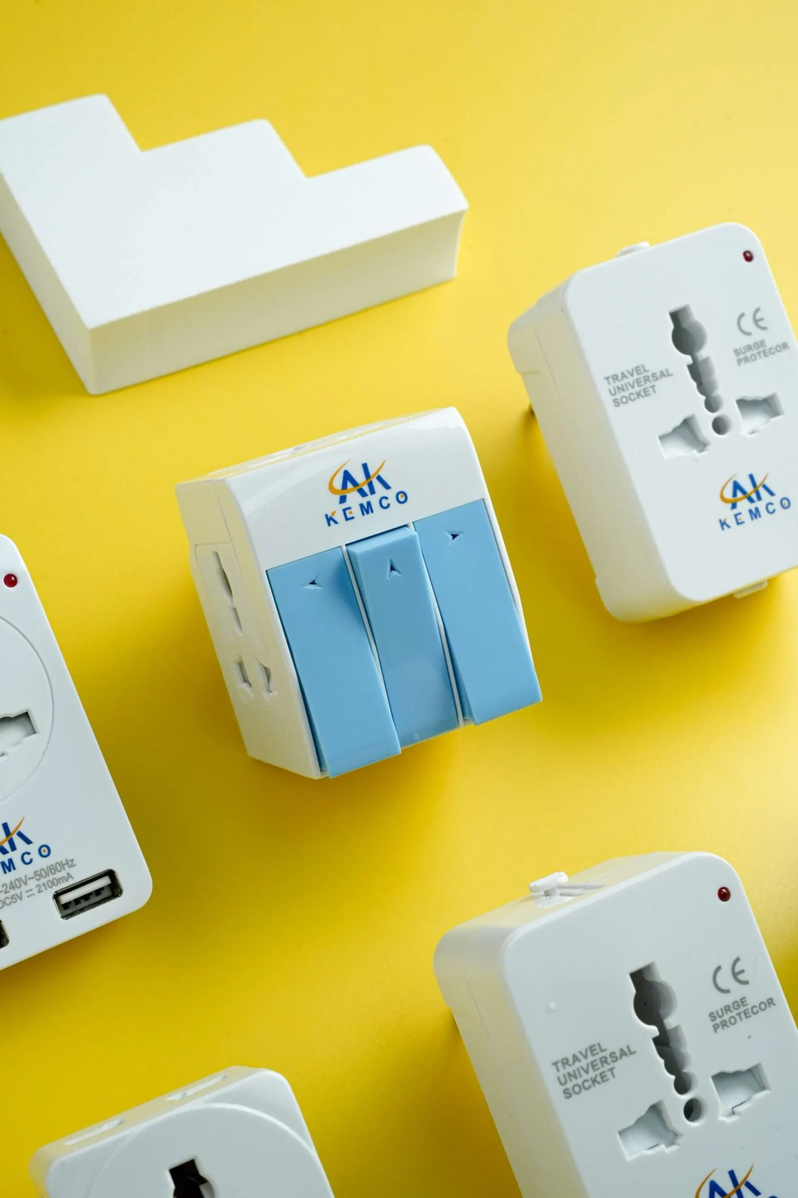 Product photography for travel and universal sockets, arranged with their cartons on a yellow background.