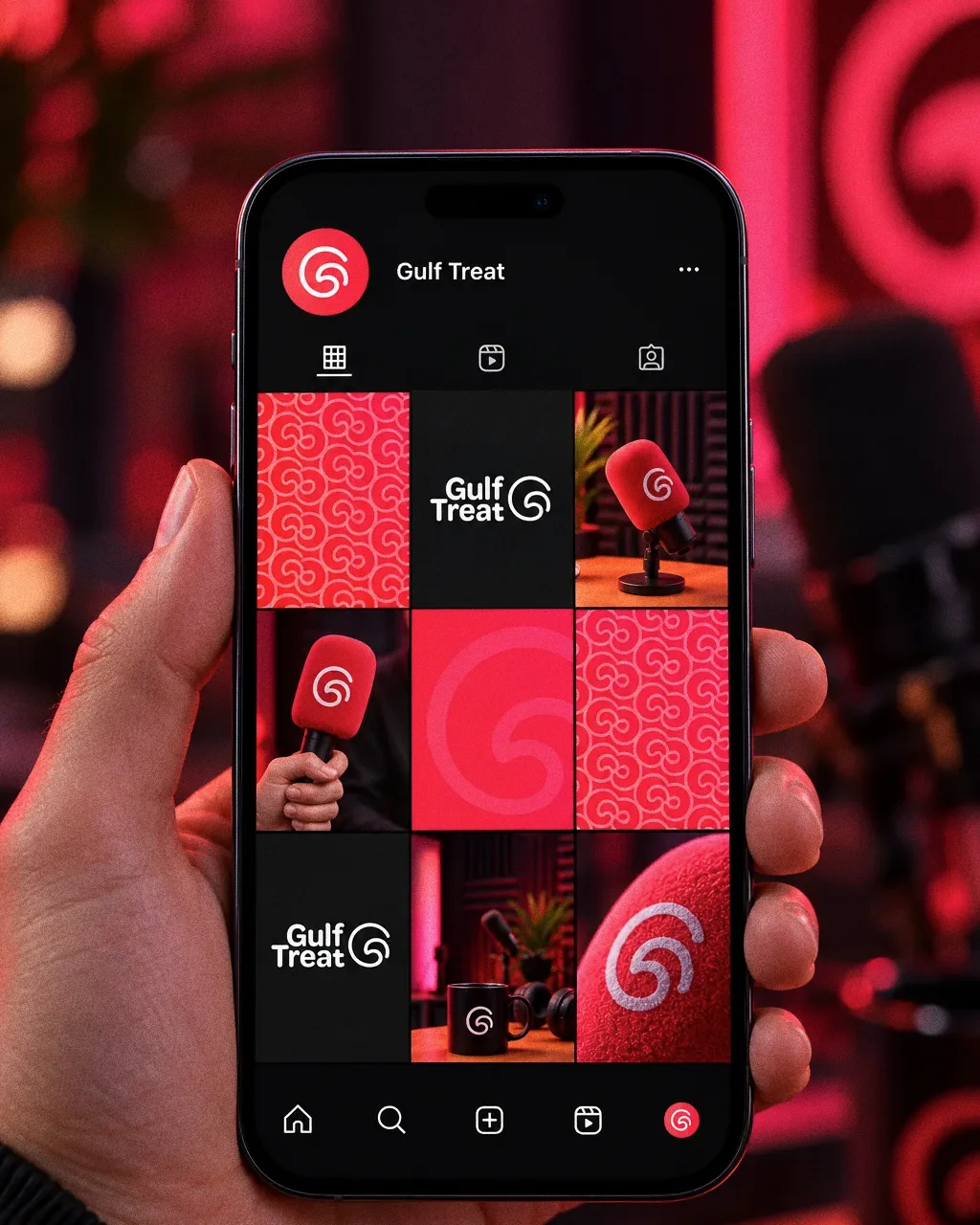 A hand holding a phone that shows a Gulf Treat Instagram grid of gradient swirl tiles and studio microphones.