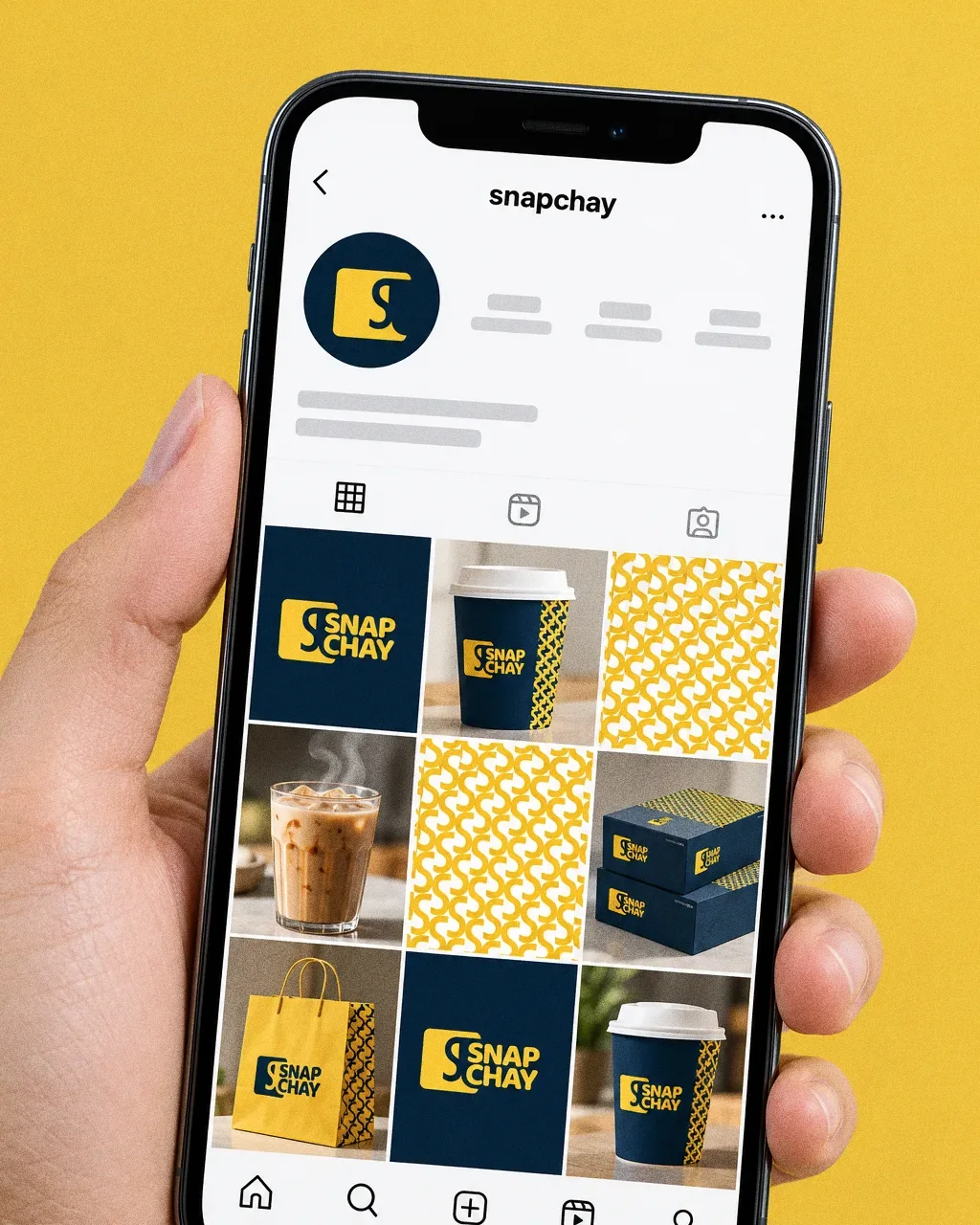 A hand holding a phone against a yellow backdrop, showing a Snap Chay Instagram grid of navy logo tiles, yellow pattern, cups, boxes and a paper bag.