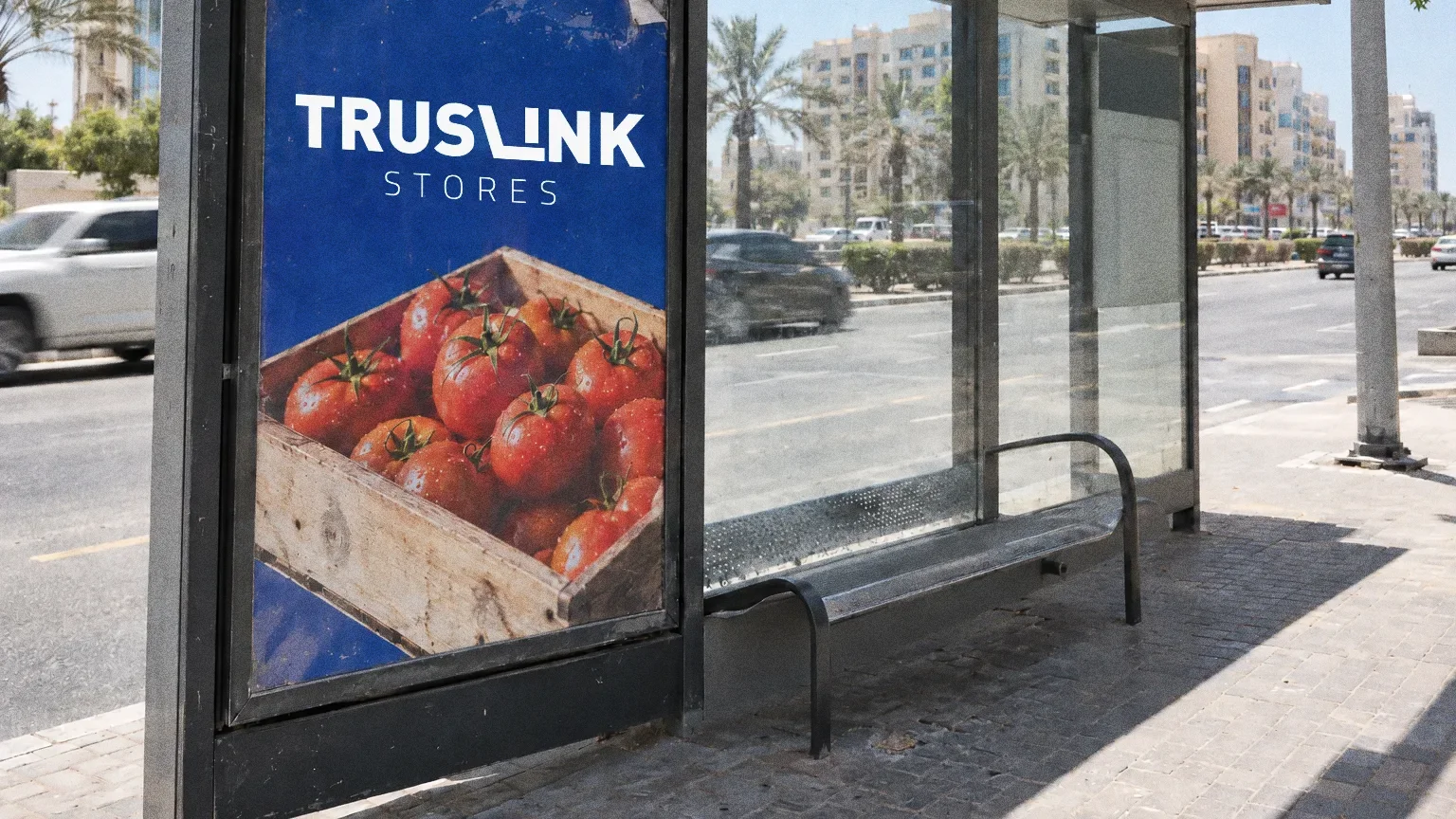 A royal blue Truslink poster in a weathered bus shelter in Al Barsha with a photo of fresh tomatoes.