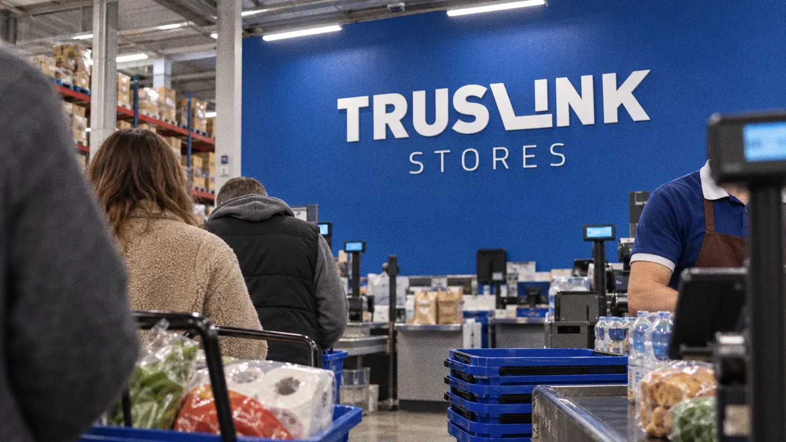 The wall above the checkout tills inside a Truslink store with the white wordmark on royal blue.